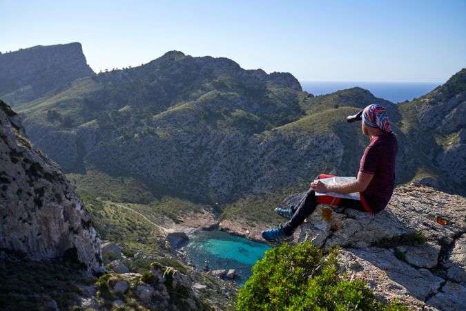 Hiker on mountain peak looking at view with binoculars