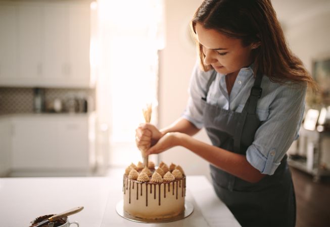 Woman decorating chocolate cake in kitchen