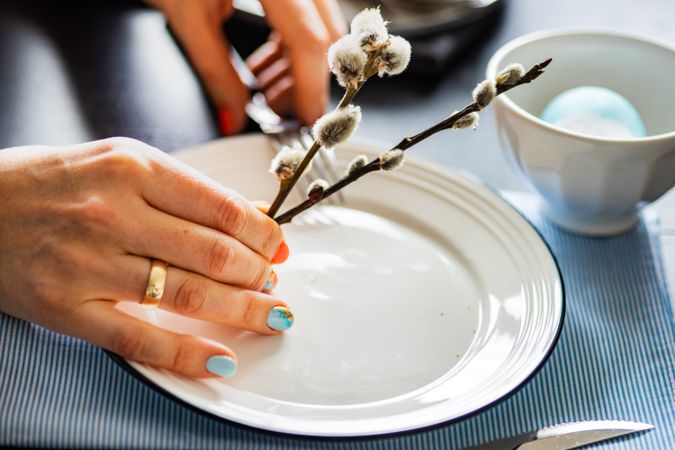 Hands of woman lifting pussy willow from Easter table setting