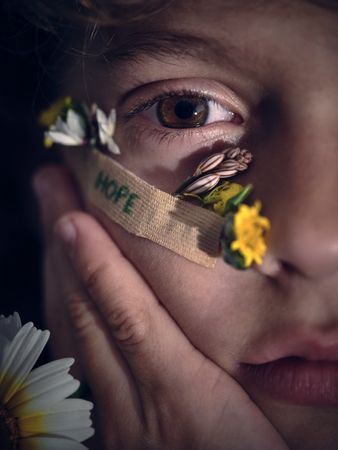 Crop boy with colorful flowers on cheek