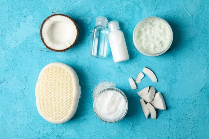 Flat lay with coconut and cosmetics on blue background, top view