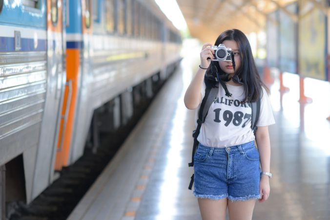 A woman holding a camera at a train platform.