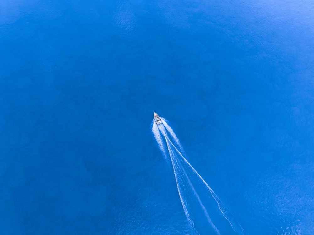Aerial view of a boar speeding across the water. People enjoying their holiday.