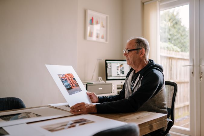 Man considering photos in his home office