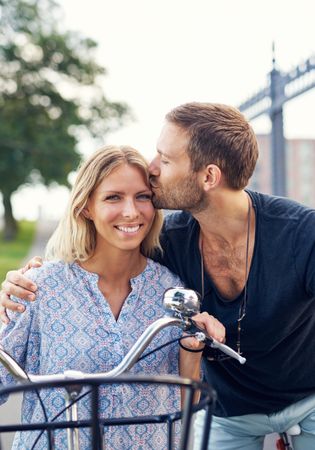 Portrait of man kissing smiling woman on a bicycle
