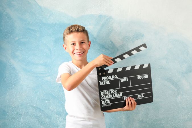 Boy with clapperboard against color background, space for text