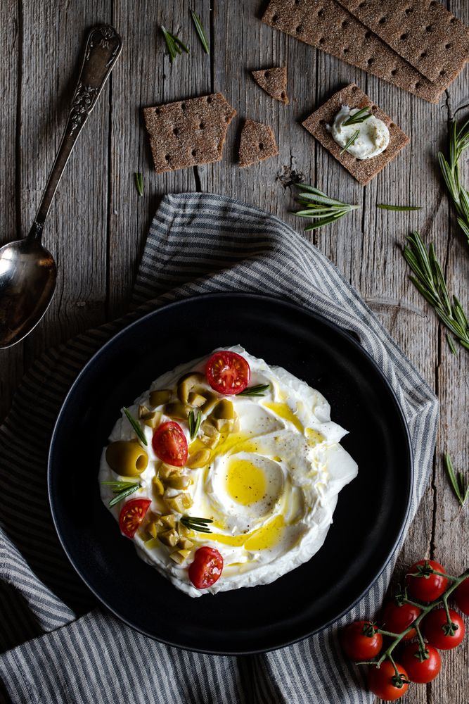 Crackers and herbs near plate with labneh