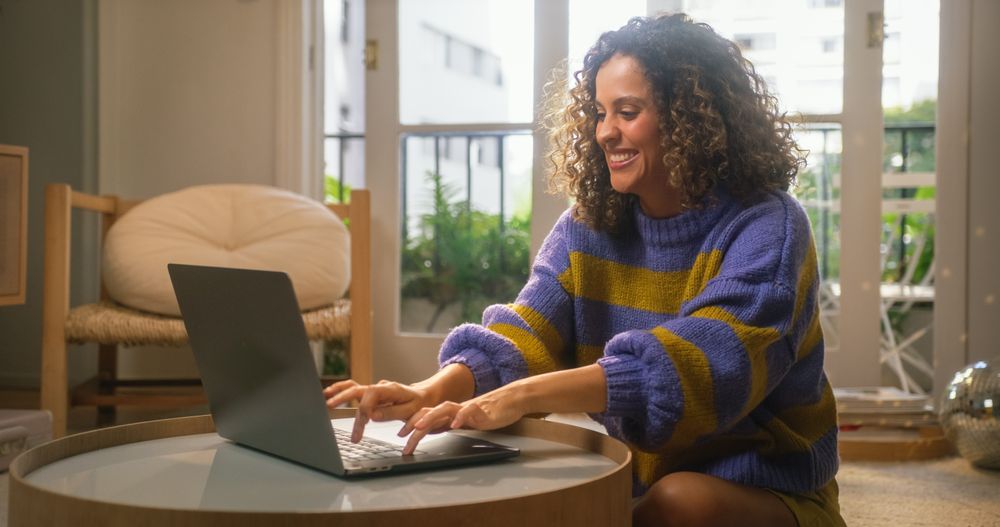 Close Up Portrait of Smiling Young Woman Working from Home on Laptop Computer in Sunny Cozy Apartment.