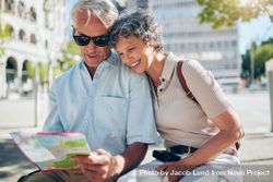Happy mature couple looking at a city map on vacation 5lRrMb