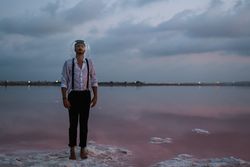 Man with fish tank on head standing at seashore