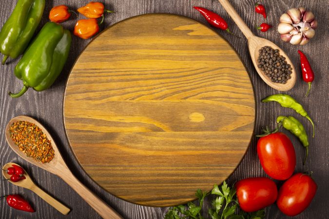 Empty pizza  board on the table with Ingredients for cooking. Tomatoes, various peppers, garlic and green peppers.
