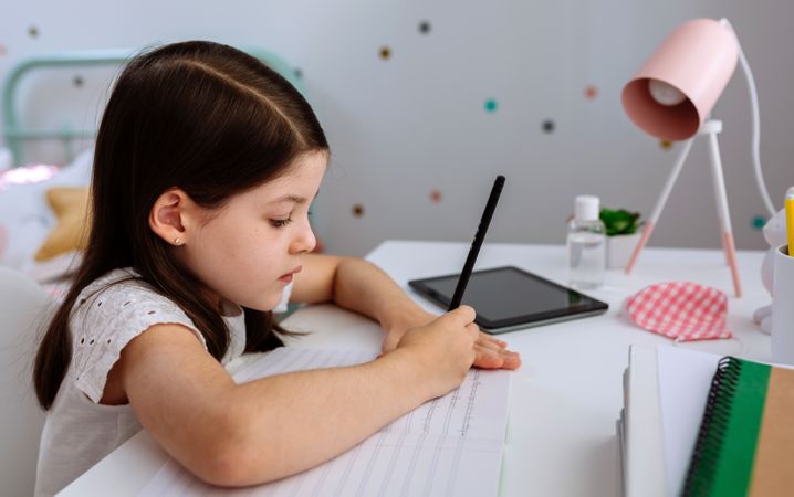 Girl studying at home with mask on table