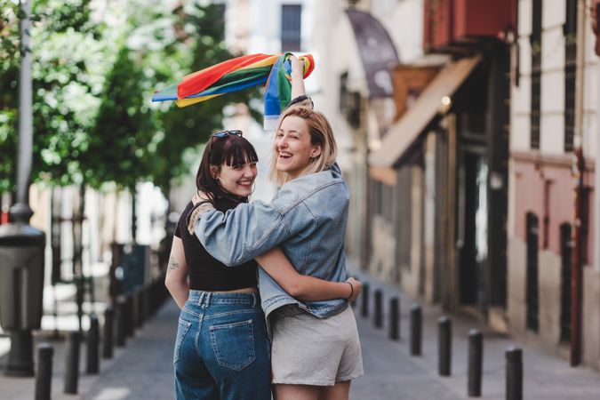 Lesbian couple with LGBT flag walking on street