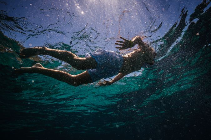 Preteen kid in diving mask snorkeling in seawater