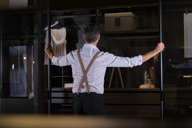 Anonymous male standing near wardrobe in dark room