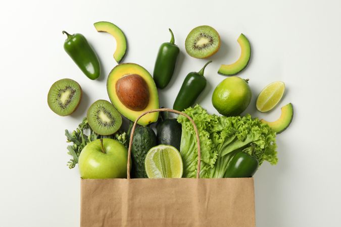 Paper bag with vegetables and fruits on blank background