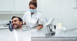 Dentist assisting a patient to wear dental bib 5lDBY5