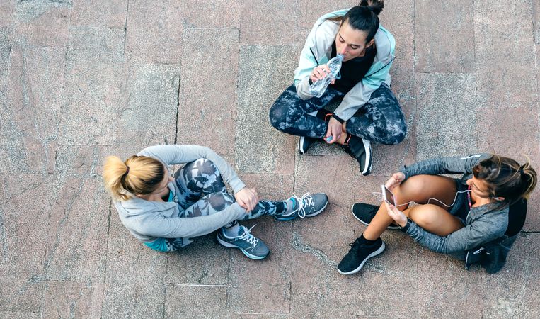 Female friends sitting on the ground after workout