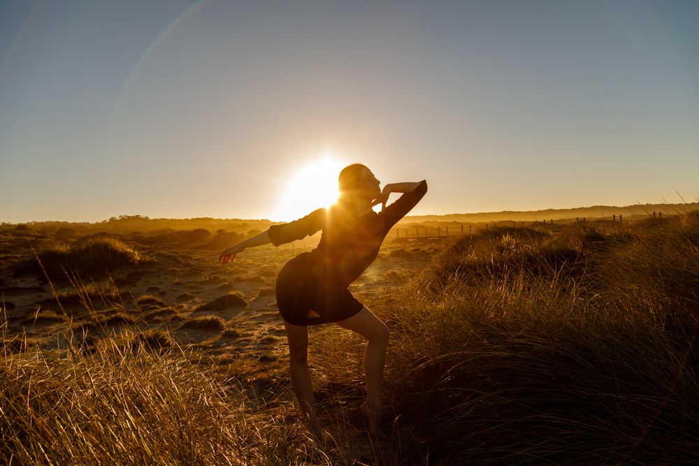 Woman posing between field at sunset