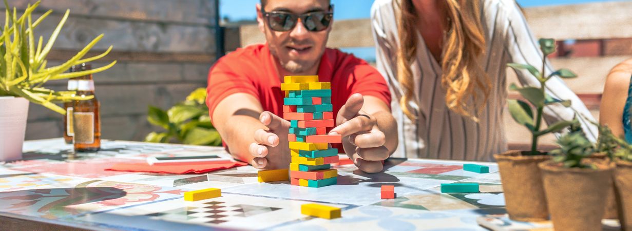 Concentrated young man pushing game piece next to female friend in rooftop party