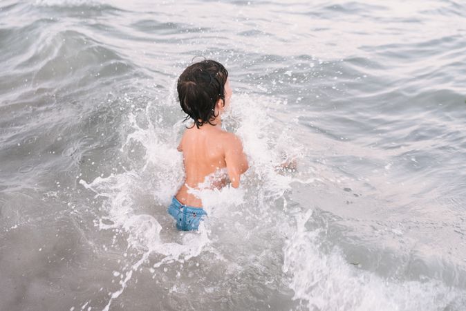 Boy walking in blue water of resort sea