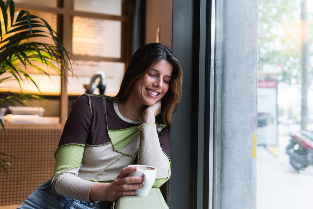 Cheerful woman with cup of coffee in cafe