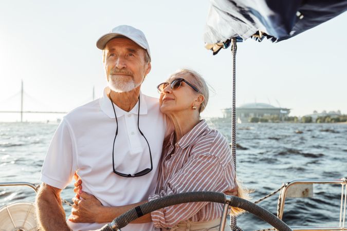 Happy older woman looking at her partner at the helm of a yacht