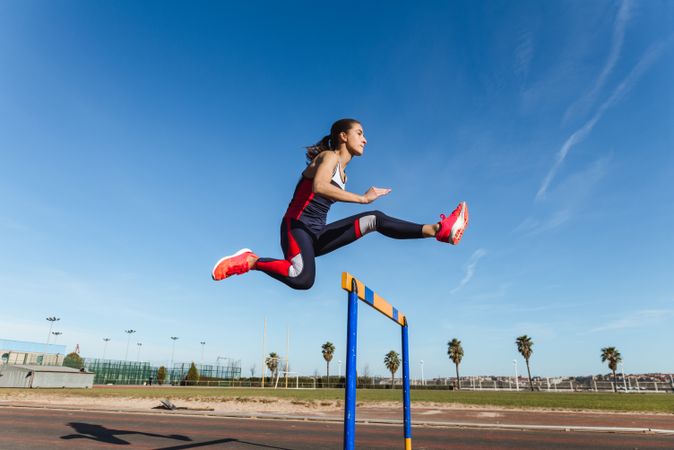 Female athlete hurdling on stadium
