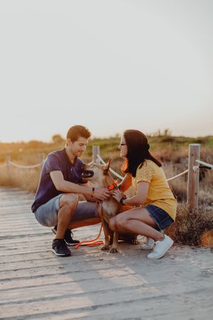 Happy adult couple petting dog at countryside