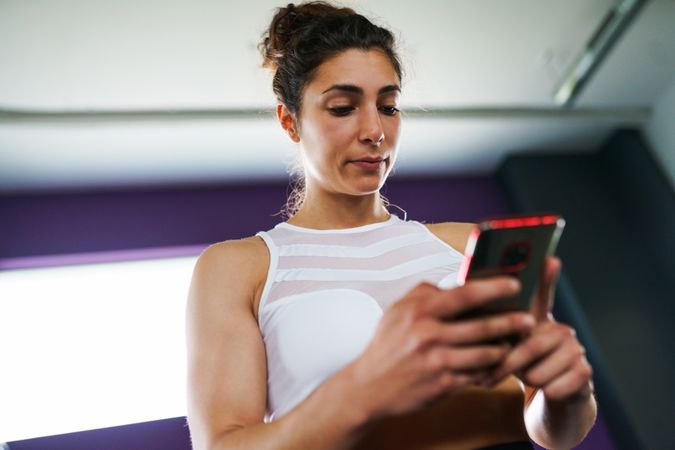 Woman looking down at her smart phone in gym