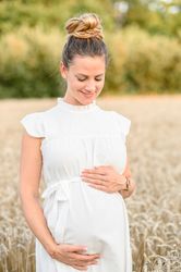 Happy pregnant woman standing in agriculture field