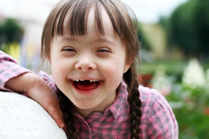 Portrait of smiling young girl with Down syndrome outside in springtime