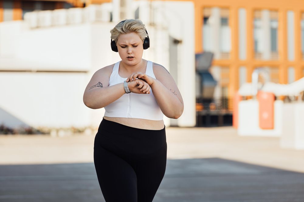 Blond woman working out outside and checking her watch