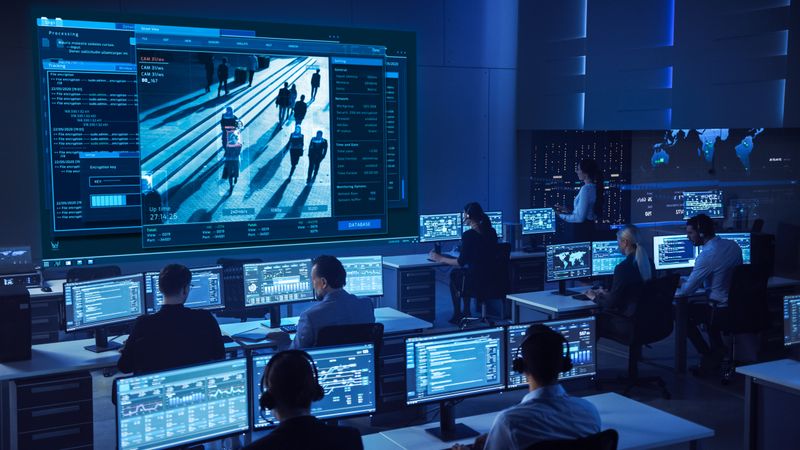 Diverse Team in a High-tech Control Room Monitors Live Surveillance Feeds, Ensuring Security and Data Integrity.