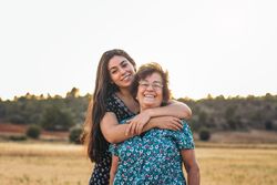 Two women of different generations in a field of sunflowers.