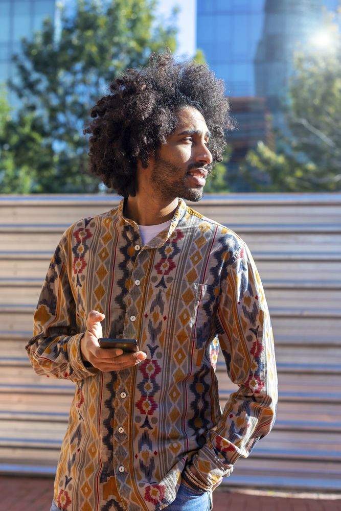 Cool young man using a mobile phone while standing outdoors on a sunny day