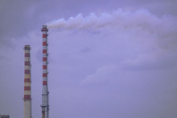 Two factory chimneys emitting industrial smoke
