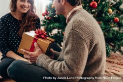 Man and woman exchanging Christmas gifts in their living room 0JGWMl