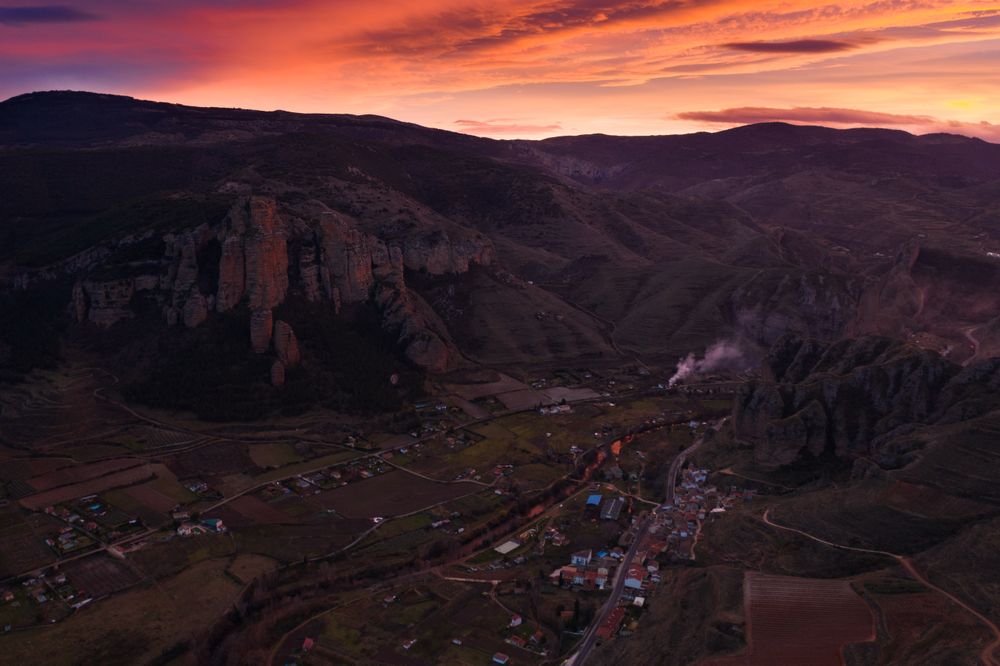 Multicoloured sunset above mountain valley and rural town