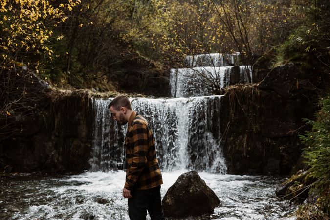 Man standing on natural stream cascade in forest