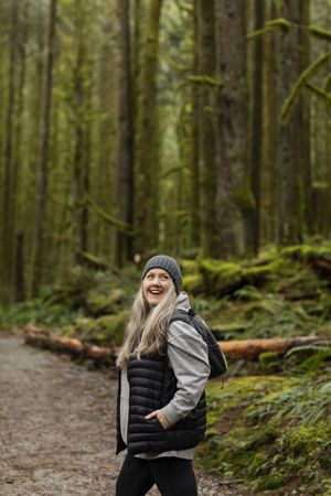 Smiling woman hiking in the woods looking upwards