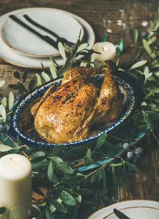 Centerpiece of roast chicken with decorative branches, candles, vertical composition