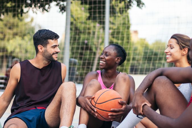 Friends sitting on the court talking after a basket game