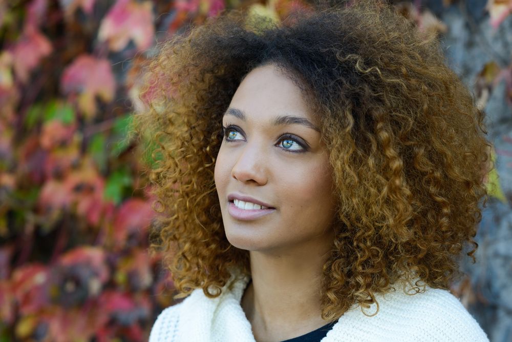 Portrait of wistful woman looking up with fall leaves in background
