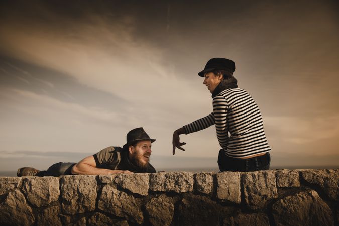Man and woman leaning out from stones