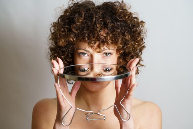 Woman holding mirror showing reflection of eyes