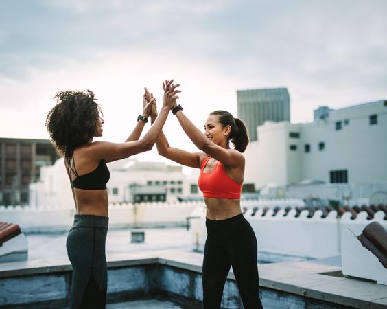 Two fitness women celebrating by giving high five after workout