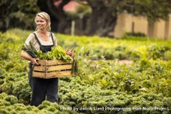 Happy farmer smiling cheerfully while walking through her vegetable garden during harvest season 5pxY85