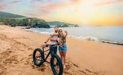 Male and female taking picture with phone standing with bicycle and dog