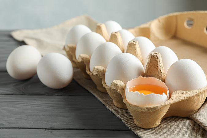 chicken eggs in carton box on wooden table, space for text